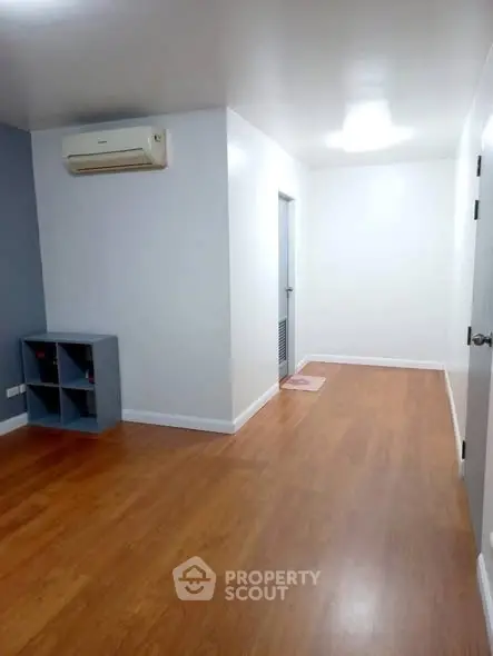 Spacious empty room with wooden flooring and air conditioning, ideal for customization.