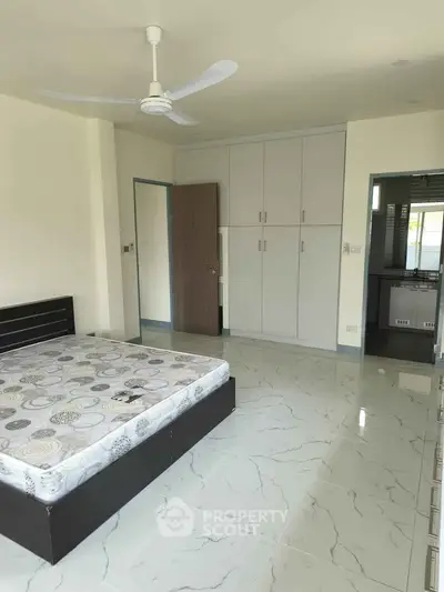 Spacious bedroom with modern design and ample natural light, featuring sleek tile flooring and built-in wardrobe.