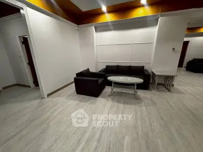 Spacious living room with modern black sofa and sleek wooden flooring