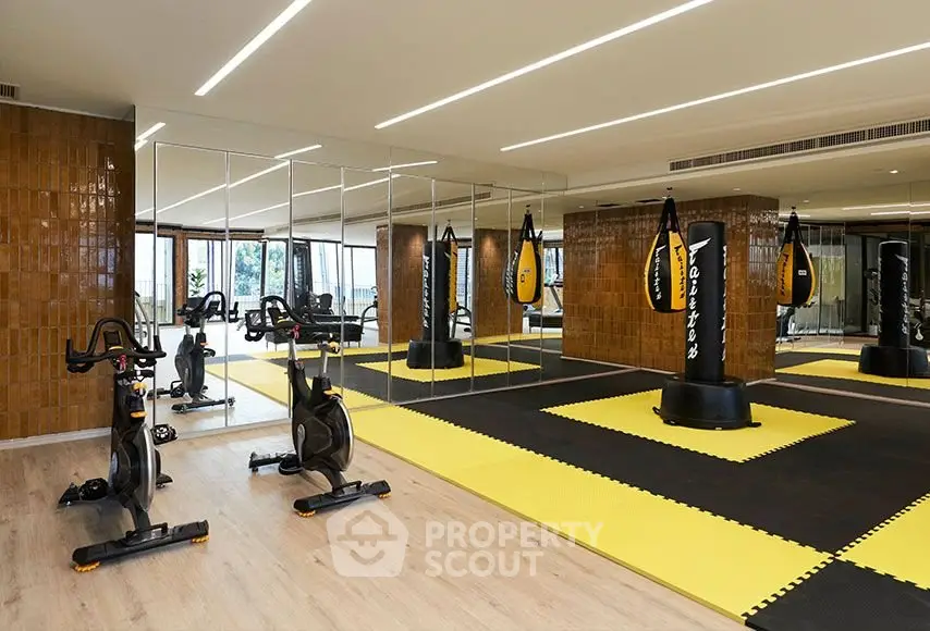 Modern gym with mirrored walls, exercise bikes, and punching bags in a luxury apartment complex.