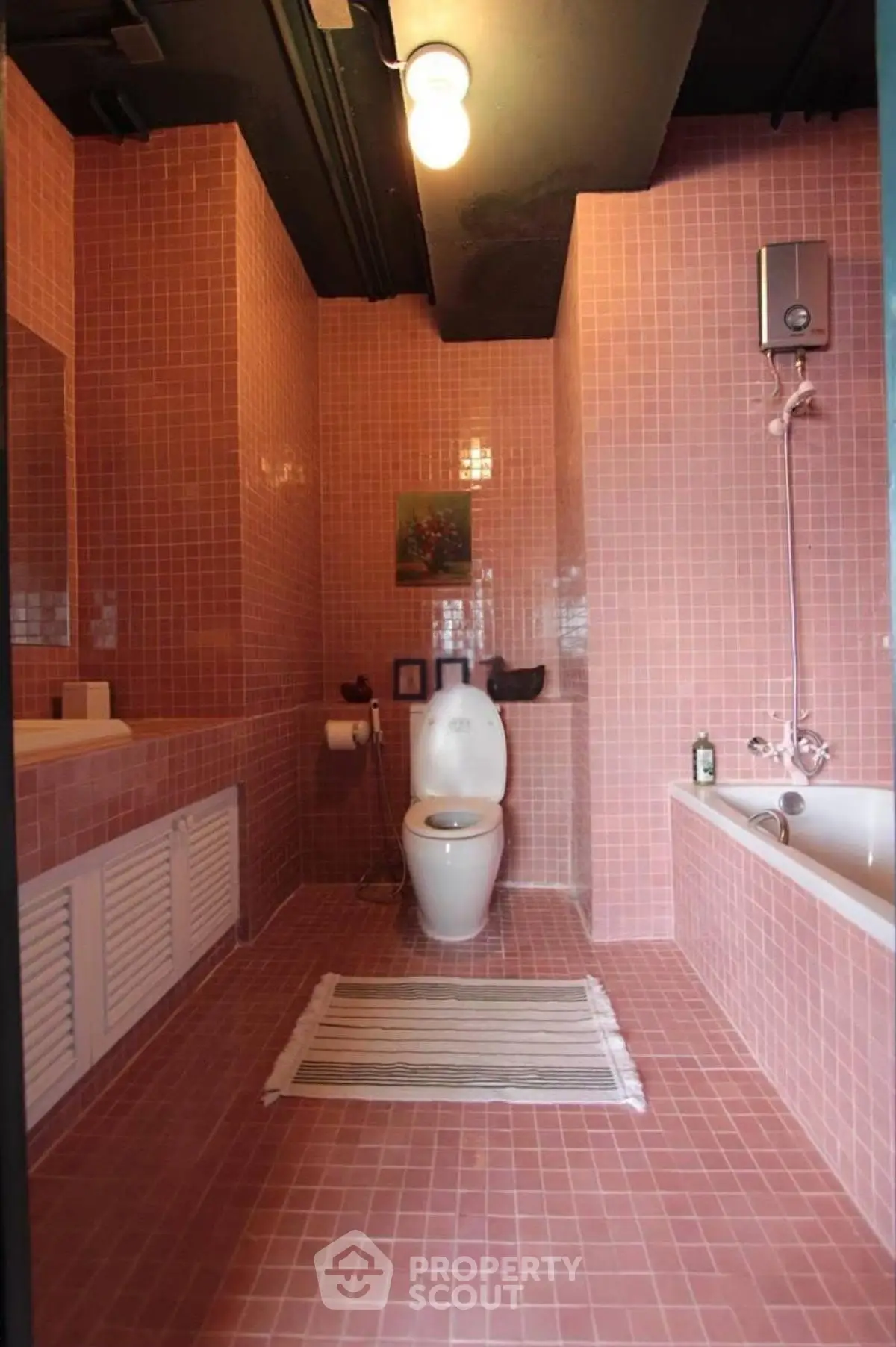 Charming pink-tiled bathroom with modern fixtures and cozy ambiance.