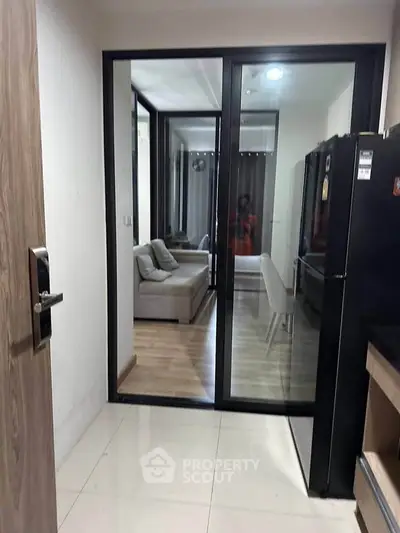 Modern apartment with sleek kitchen and cozy living area, featuring glass sliding doors and contemporary design.