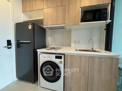Modern kitchen with sleek appliances and wooden cabinetry in a stylish apartment.