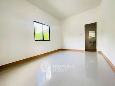 Spacious unfurnished room with glossy tiled floor and window view.