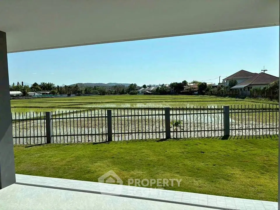Stunning view from a modern home overlooking lush green fields and distant houses.