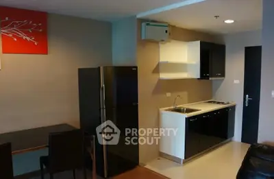Modern kitchen with sleek black and white cabinetry and dining area in stylish apartment.