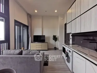 Modern living room with sleek kitchen and washing machine, featuring a cozy sofa and flat-screen TV.