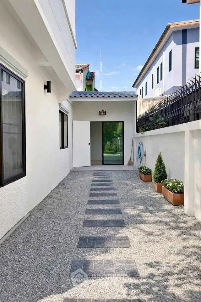 Charming exterior walkway with modern design and lush greenery, perfect for serene outdoor living.