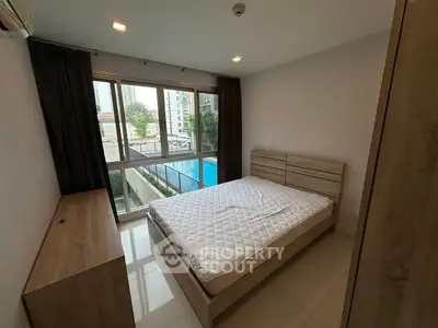 Modern bedroom with large window and pool view in urban apartment