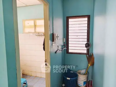 Compact utility room with blue walls, window, and cleaning supplies, ideal for efficient home organization.