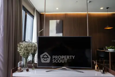 Modern living room with stylish decor and large TV, featuring elegant lighting and wooden accents.
