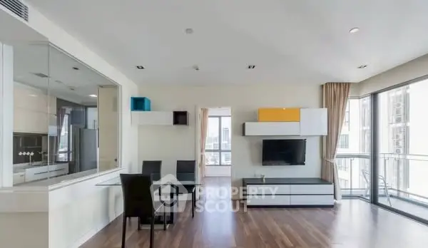 Modern living room with sleek furniture and large windows offering city views.