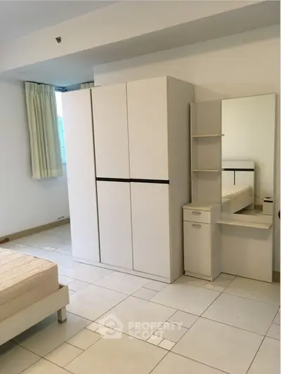 Spacious bedroom with modern wardrobe and vanity in a bright apartment.