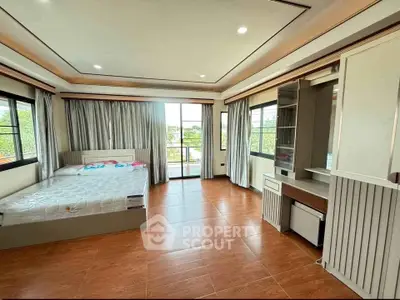 Spacious bedroom with large windows and balcony access, featuring elegant wood flooring and modern furnishings.