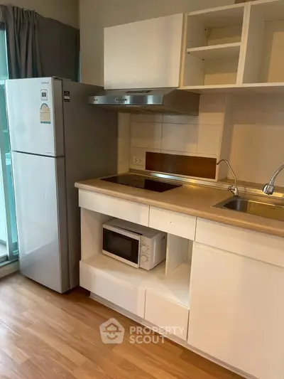 Modern kitchen with sleek cabinets, stainless steel appliances, and wooden flooring in a cozy apartment.