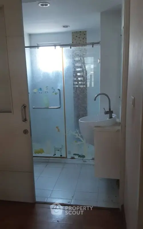 Modern bathroom with glass shower and sleek sink in stylish apartment.