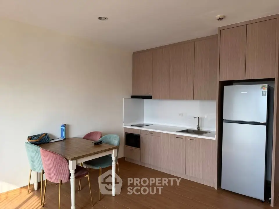 Modern kitchen with sleek cabinetry and dining area in cozy apartment