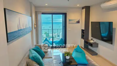 Modern living room with ocean view, stylish decor, and large TV in a high-rise apartment.