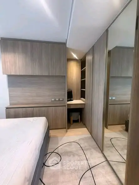 Modern bedroom with sleek wooden cabinetry and mirrored closet doors, offering ample storage space.