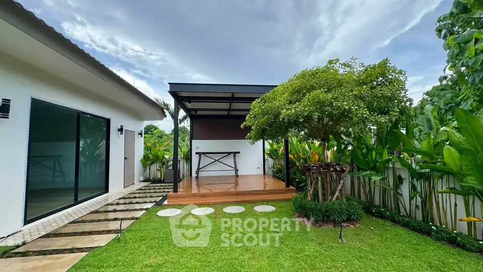 Stunning modern home with lush garden and spacious deck, perfect for outdoor living.