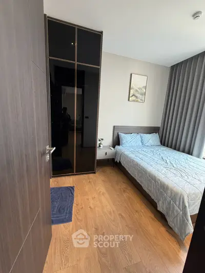 Modern bedroom with wooden flooring, stylish wardrobe, and cozy bed in a contemporary apartment.