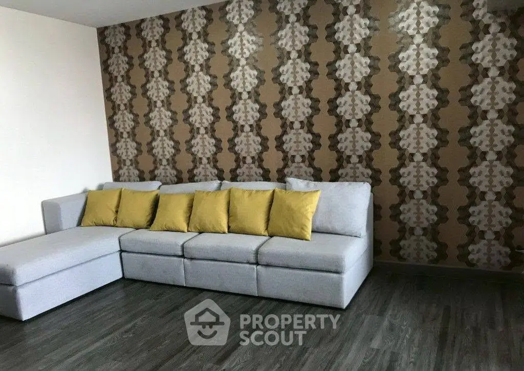 Stylish living room with modern sectional sofa and unique patterned wallpaper, perfect for contemporary living.