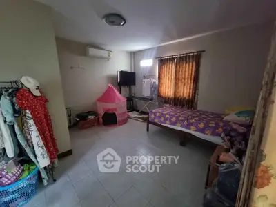 Cozy bedroom with single bed, TV, and air conditioning in a well-lit space.