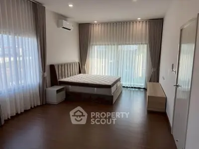 Spacious bedroom with large windows and modern furnishings, perfect for comfort and relaxation.