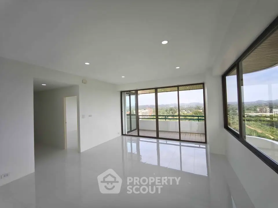Spacious modern living room with large windows and balcony offering stunning views.