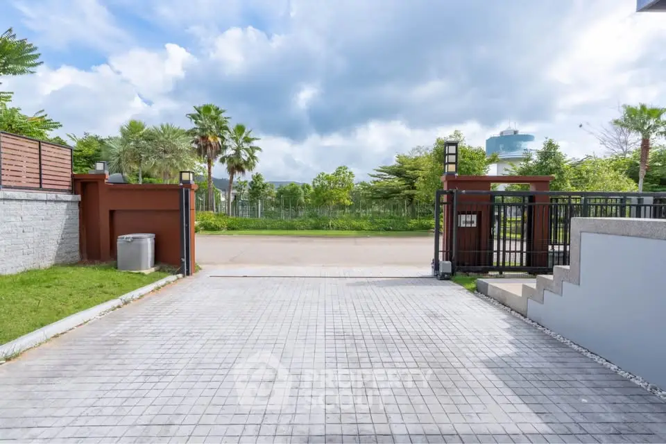 Spacious driveway entrance with lush greenery and modern gate design