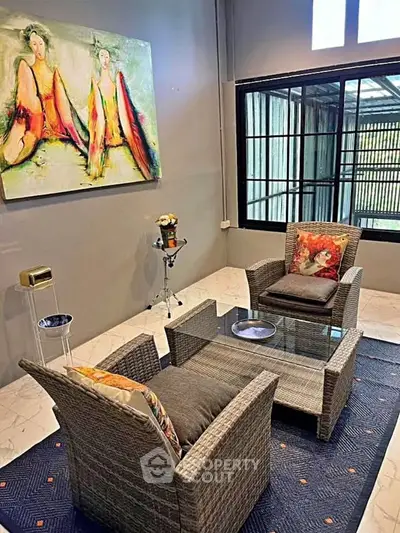 Stylish living room with modern wicker furniture and vibrant artwork, perfect for relaxation.