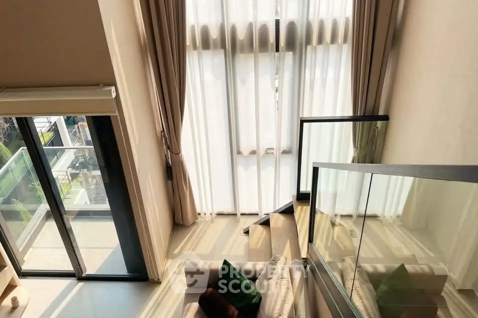 Luxurious modern living room with floor-to-ceiling windows and balcony access, offering abundant natural light.