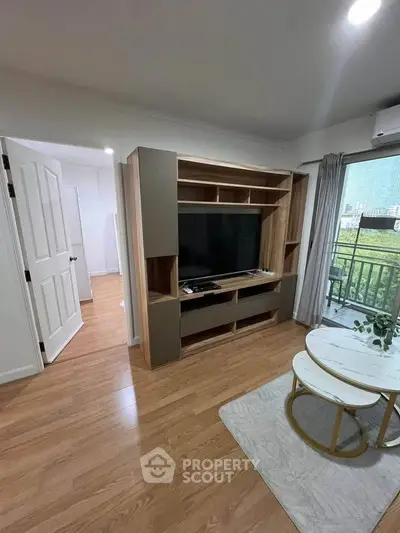 Modern living room with wooden flooring, stylish TV unit, and balcony view in a contemporary apartment.