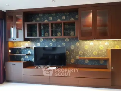 Elegant living room with stylish wooden entertainment unit and floral wallpaper accent.