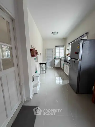 Modern kitchen with sleek appliances and glossy tile flooring, featuring a spacious layout and natural light.