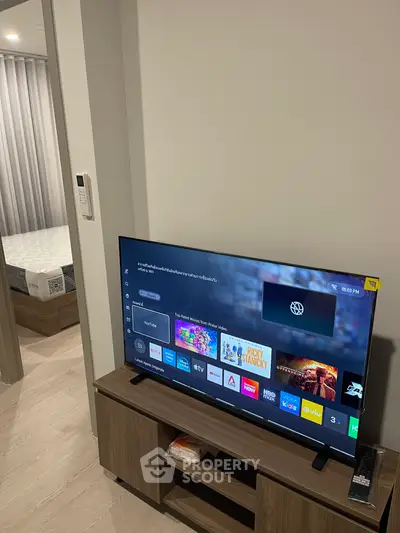 Modern living room with sleek TV setup and glimpse of cozy bedroom