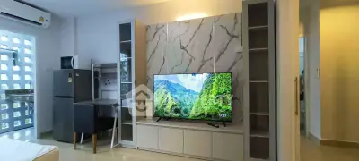 Modern living room with stylish TV unit and marble accent wall in a bright apartment.