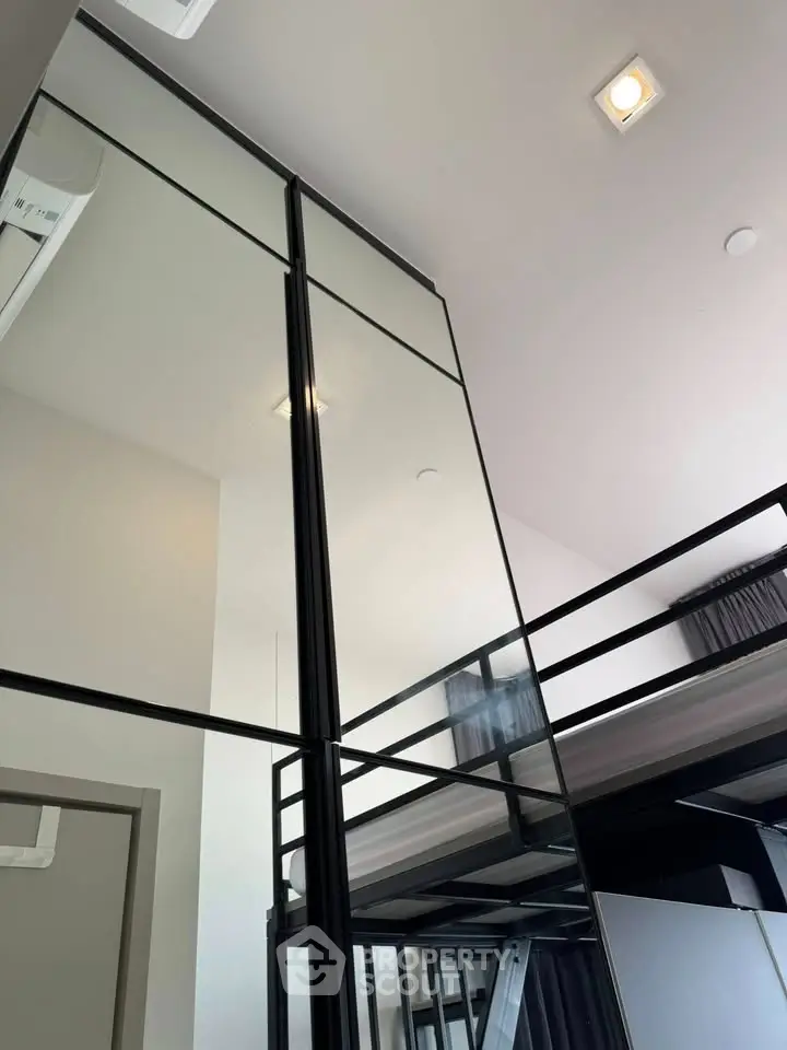Modern loft-style interior with high ceilings and sleek mirrored wardrobe.
