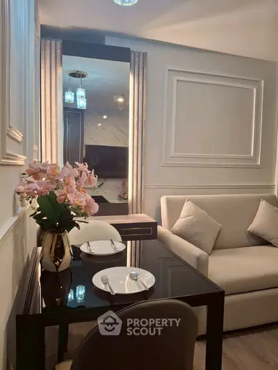 Elegant living room with modern decor, featuring a cozy sofa and stylish dining area with floral centerpiece.