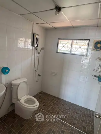 Spacious bathroom with modern shower and tiled flooring in a well-lit setting.