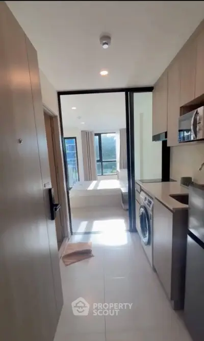 Modern apartment with sleek kitchen and bright living area, featuring built-in appliances and large windows.