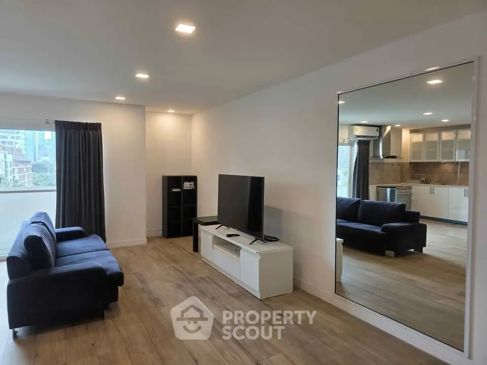 Spacious modern living room with sleek furniture and large mirror, ideal for urban living.
