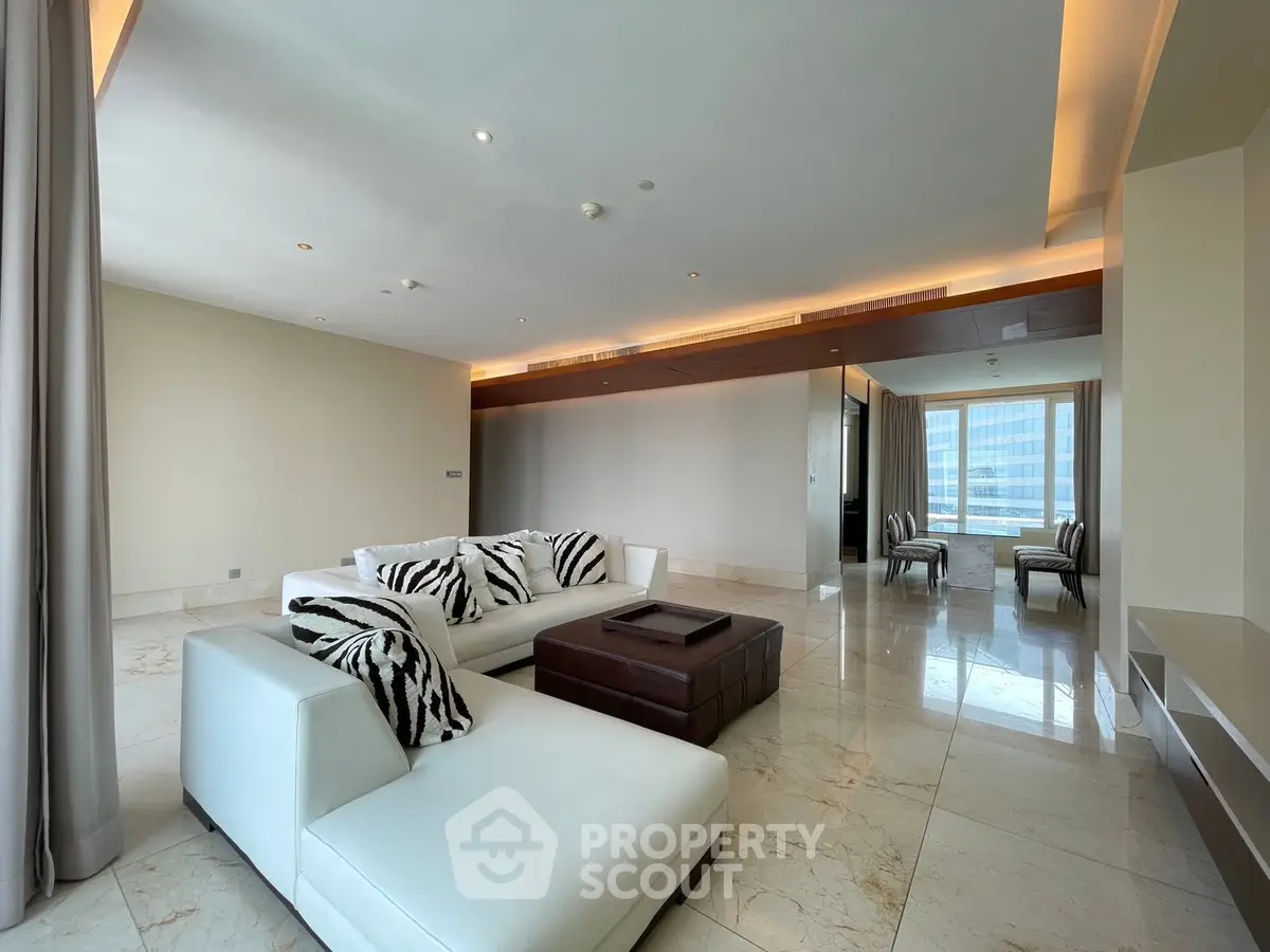 Luxurious modern living room with elegant white furniture and marble flooring, featuring a spacious open layout.