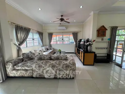 Spacious living room with elegant floral sofa and large windows offering natural light.
