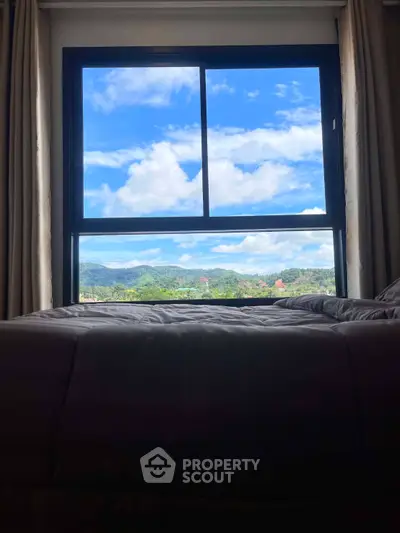 Stunning bedroom view with large window overlooking scenic mountains and blue sky.