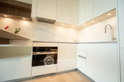 Modern kitchen with sleek white cabinetry and built-in oven