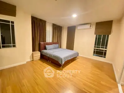 Spacious bedroom with wooden flooring and modern furnishings in a cozy apartment.