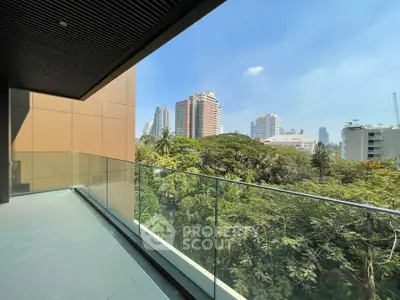Spacious balcony with glass railing offering stunning city and greenery views.