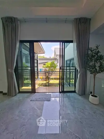 Spacious living room with large glass doors opening to a serene garden view, perfect for relaxation.