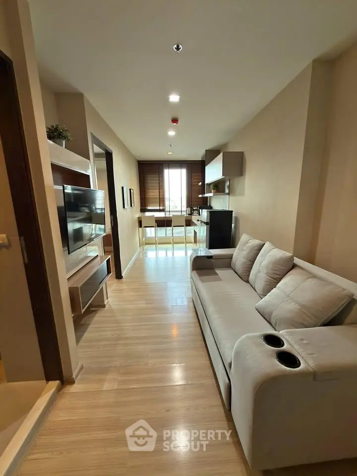 Modern living room with sleek design and natural light, featuring a comfortable sofa and wall-mounted TV.